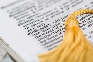 Close-up image of a dictionary page focused on the word 'dictionary' with a yellow tassel.